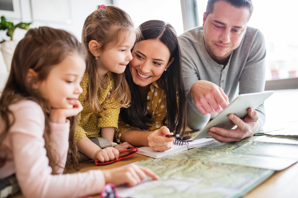 Young happy family with two children and tablet preparing a trip.