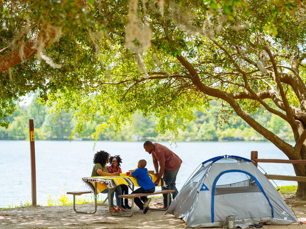 A young family tent camping by a small lake.