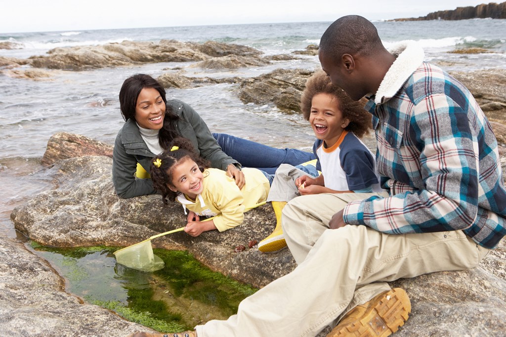 Young family with fishing net on rocks enjoying day at beach