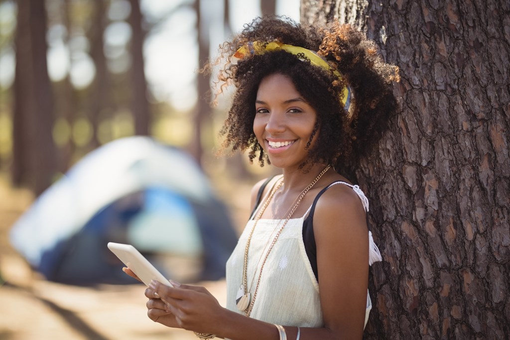 Woman smiling as she uses her phone at her KOA campsite.