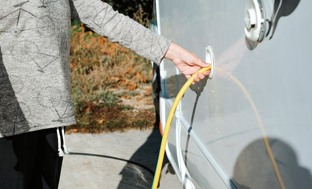 Close-up of a woman's hand filling the water tank of a motorhome.