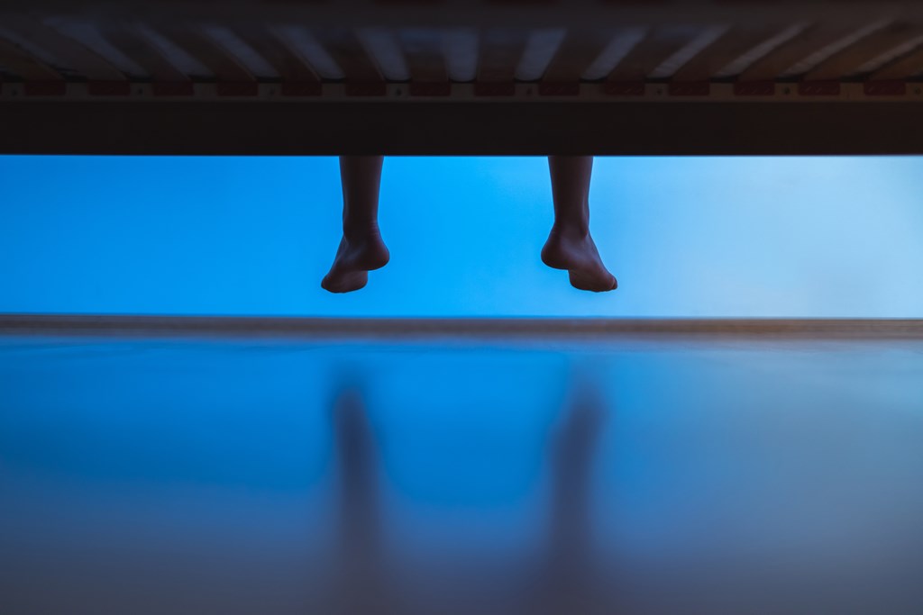 A man's legs hanging off the end of the bed helps introduce the kids ghost story called Thing at the End of the Bed
