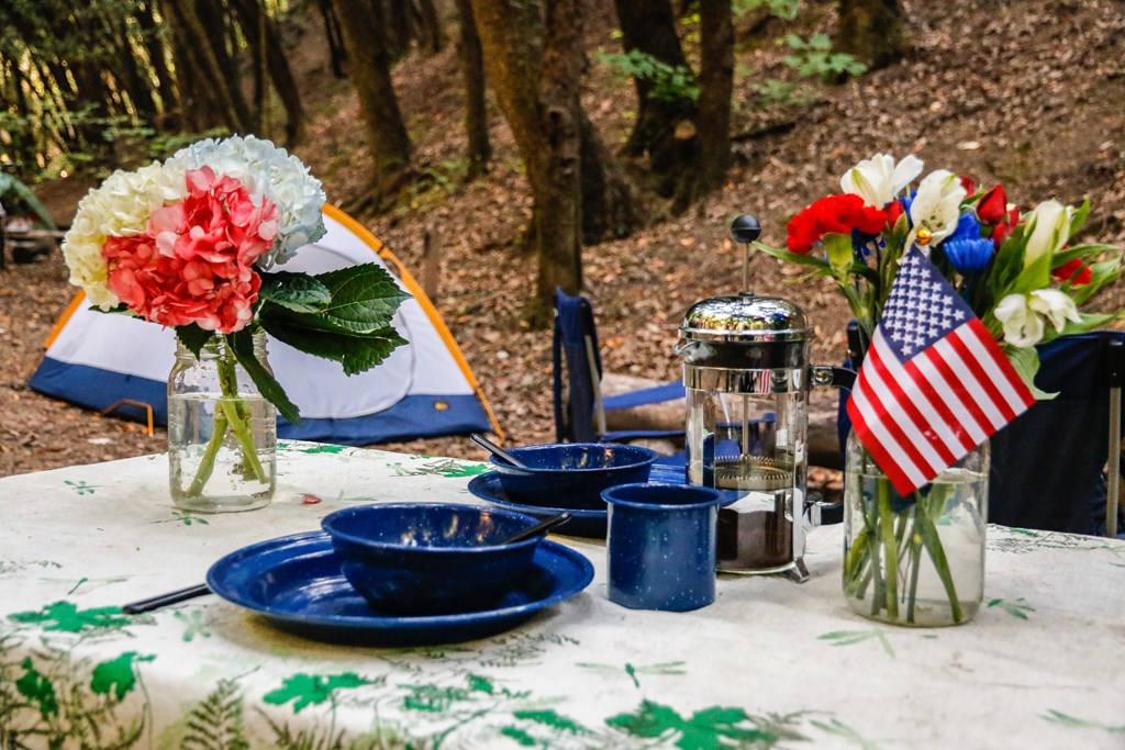Table set for Fourth of July at a campsite with a tent.