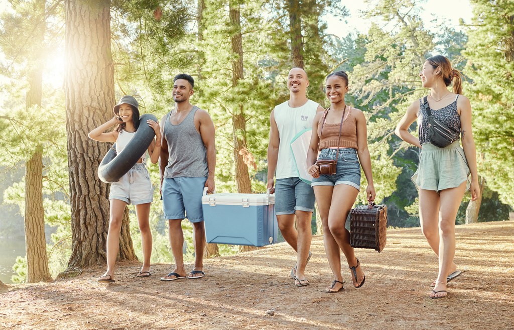 A group of five friends walks down a trail to setup for an afternoon outdoors.