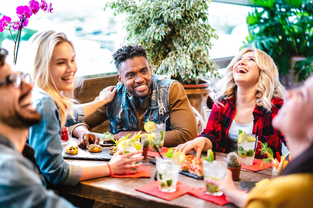 A group of friends enjoying appetizers and cocktails at an outdoor restaurant.