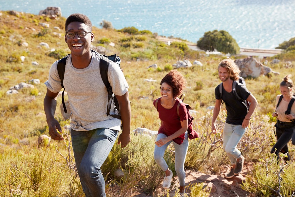 Group of young adult friends hike up a hill together.