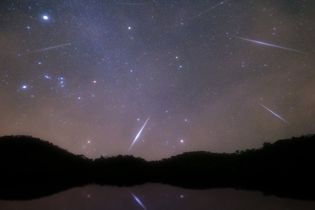 Geminid Meteor in the night sky or a mountain lake.