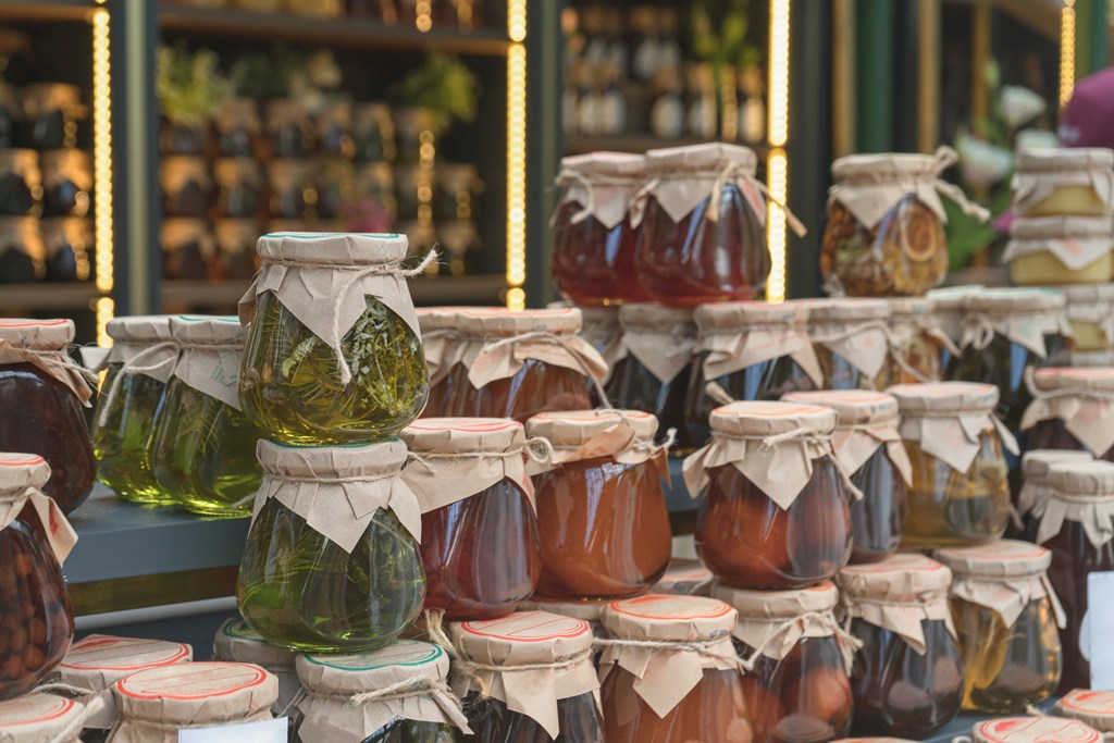 Market stall displaying a bunch of stacked colorful glass jars of jam. 