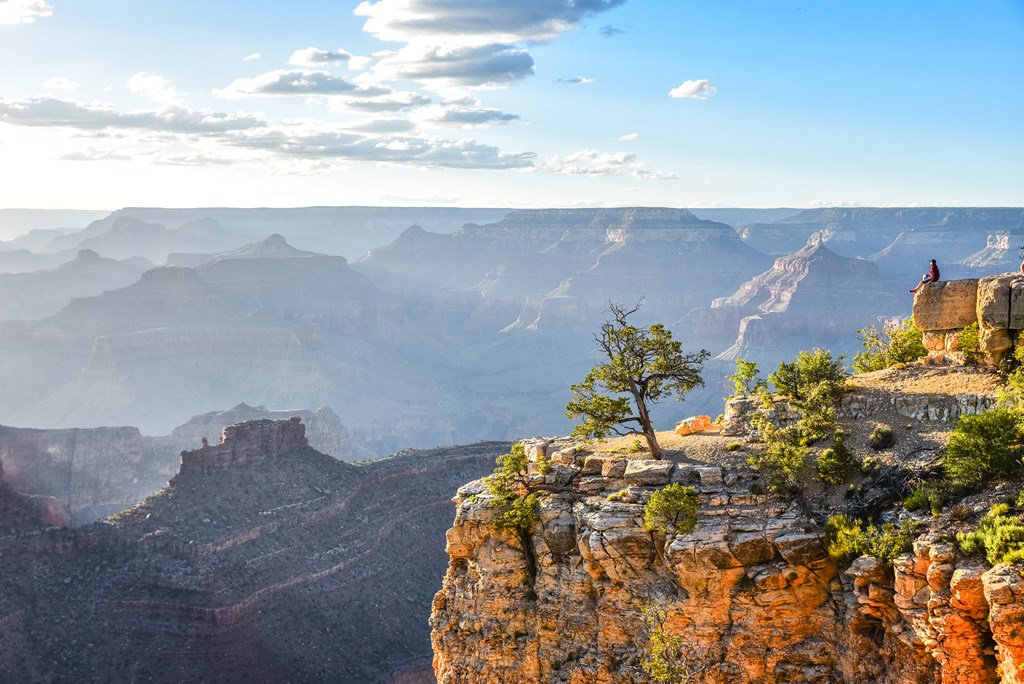 A hiker views the dramatic cliffs of the grand canyon during sunset.