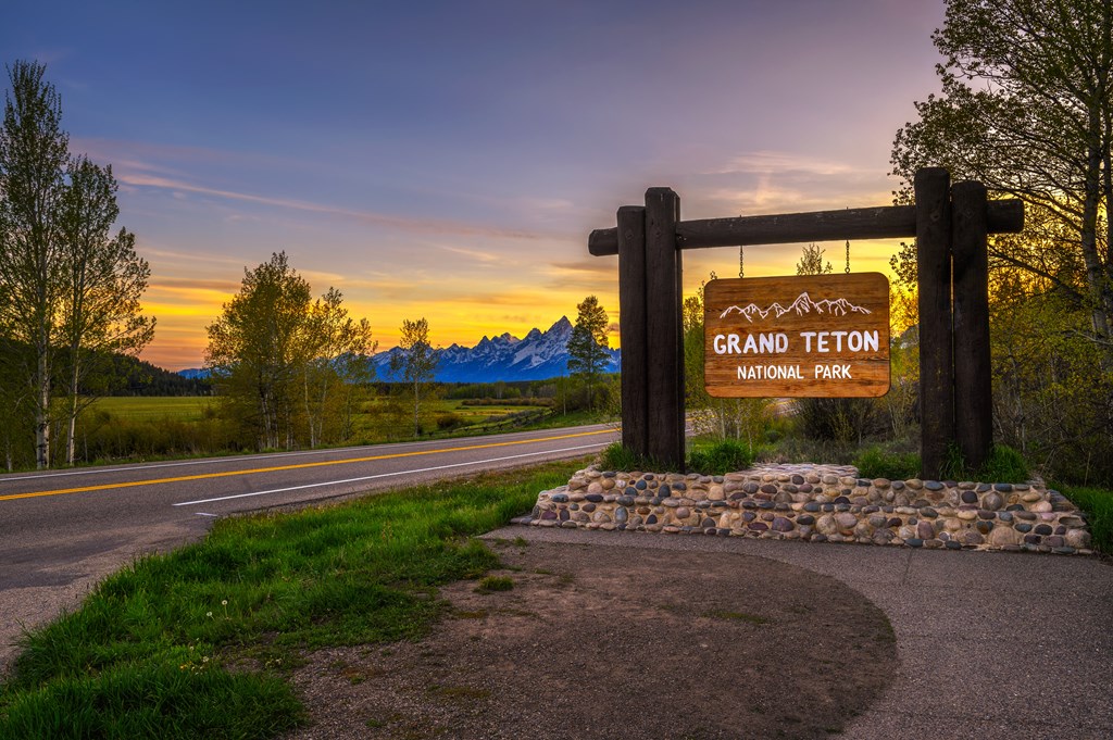 Welcome sign at the entrance to Grand Teton National Park in Wyoming, with Teton Mountain Range in the background. Photographed at sunset.