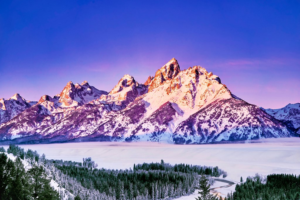A magnificent sunrise painting the Grand Teton Mountains colorful on a winter day.