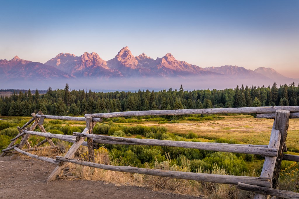 View of Grand Teton Mountains at dusk rising from mist.