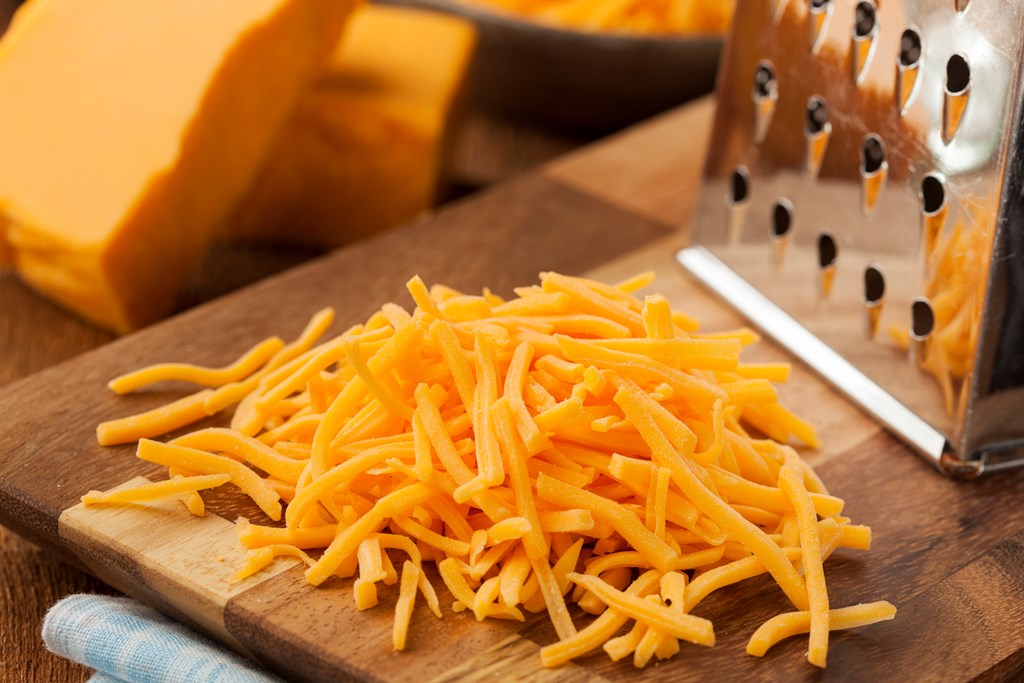 Shredded Sharp Cheddar Cheese on a Cutting Board