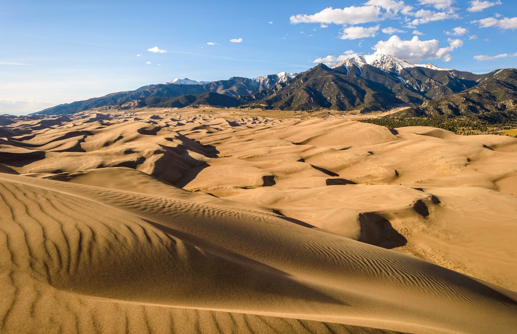 Sunset view of rolling waves of sand dunes at base of Mt Herard in Great Sand Dunes National Park and Preserve.