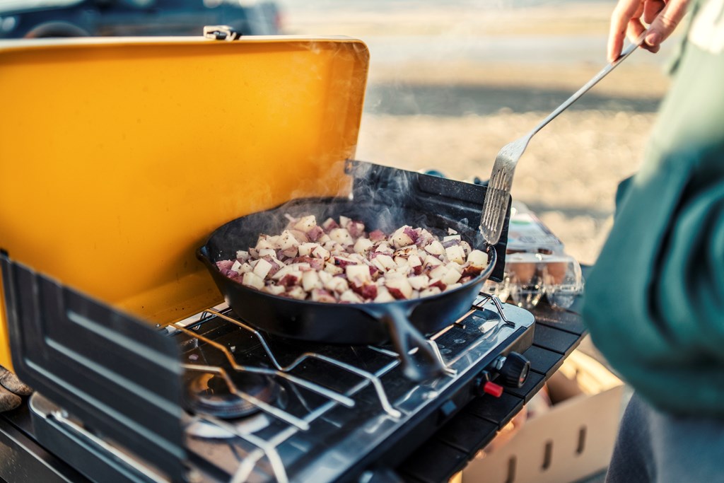 Preparing camp breakfast on gas stove at sunrise in Flaming Gorge, Utah, United States.