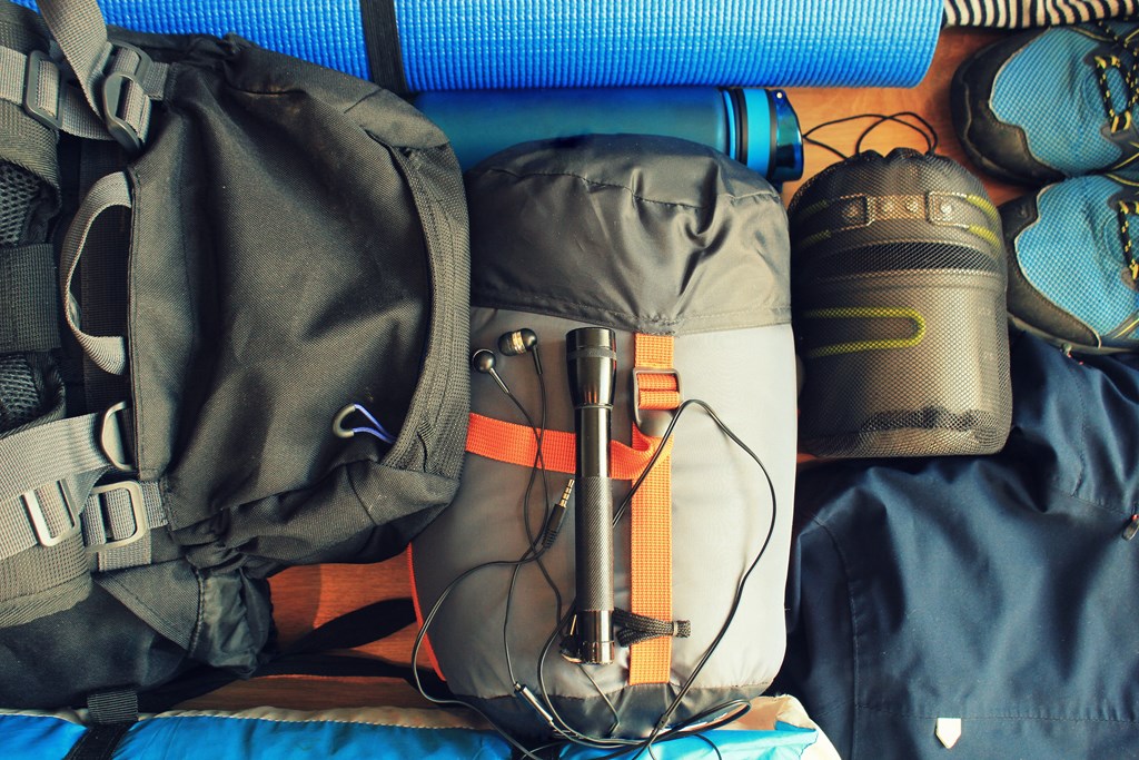 Flat lay composition with camping equipment on wooden background.