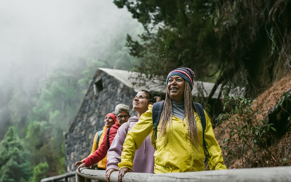Group of women with different ages and ethnicities having fun walking in foggy forest.