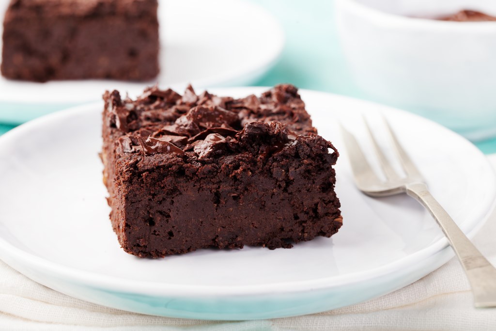 Chocolate brownie, cake on a white plate on a turquoise wooden background