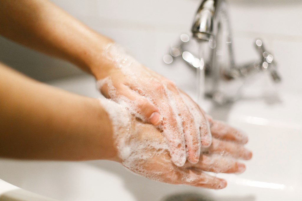 Hands washing with soap foam on background of water flowing from faucet. 