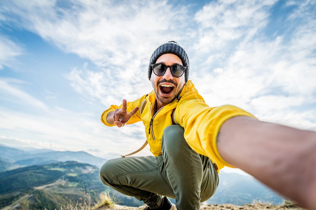 Young man on a mountain hike takes a selfie.