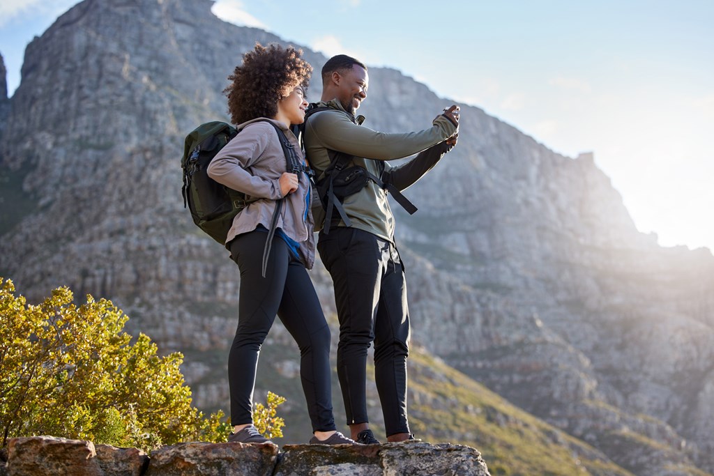 Two hikers taking a photo against a rugged mountain backgrop.