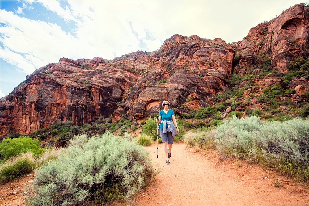 A senior woman hiking in a red rock sandstone canyon.