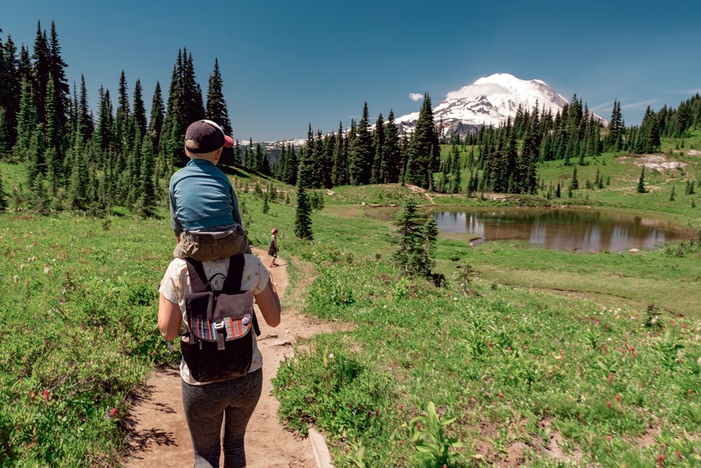 Young mother carrying son toward Mt Rainier on the Naches Peak Loop Trail in Mt. Rainier National Park.