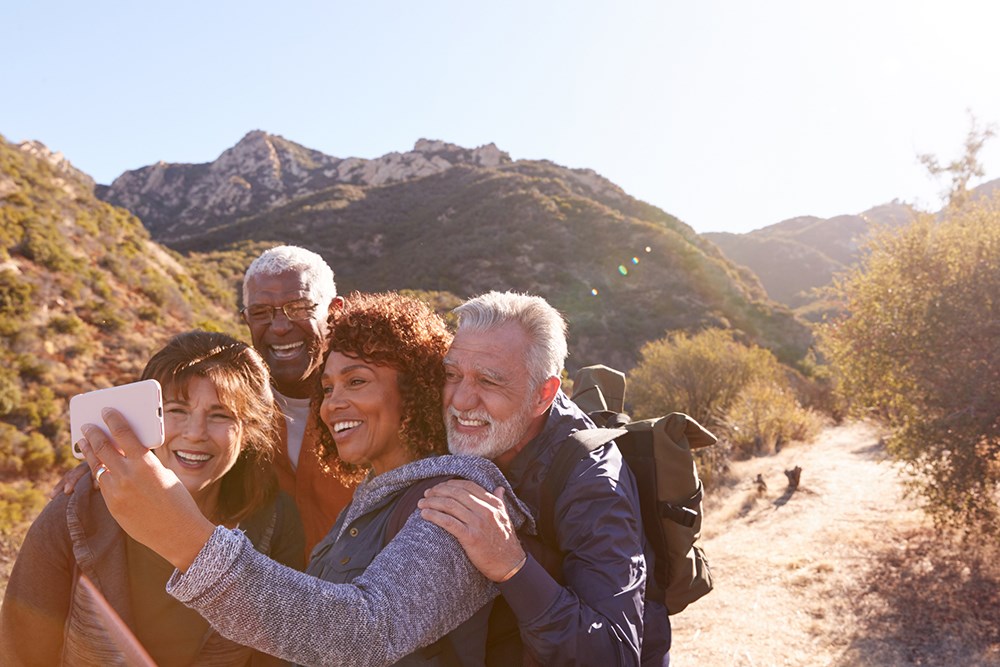 Group Of Friends Posing For Selfie As They Hike Along Trail.