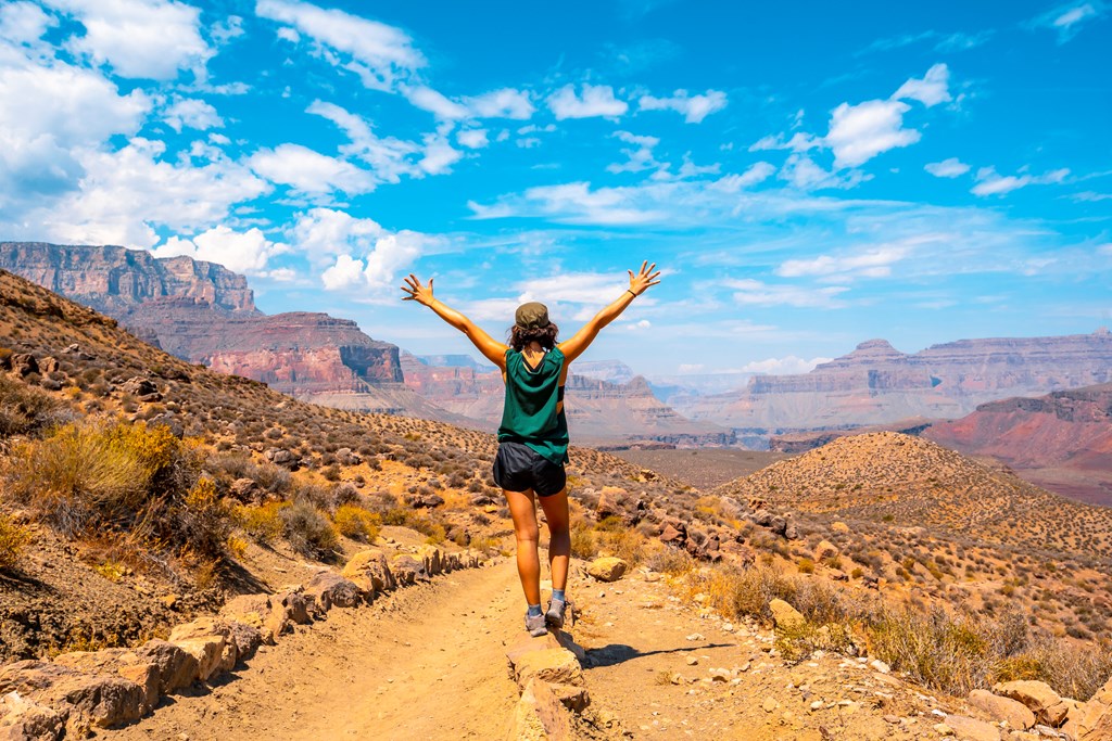A young woman with open arms on the South Kaibab Trailhead in Arizona.