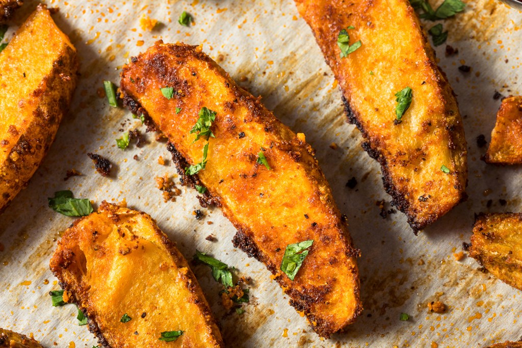 Homemade potato wedges on a backing sheet with parchment paper.