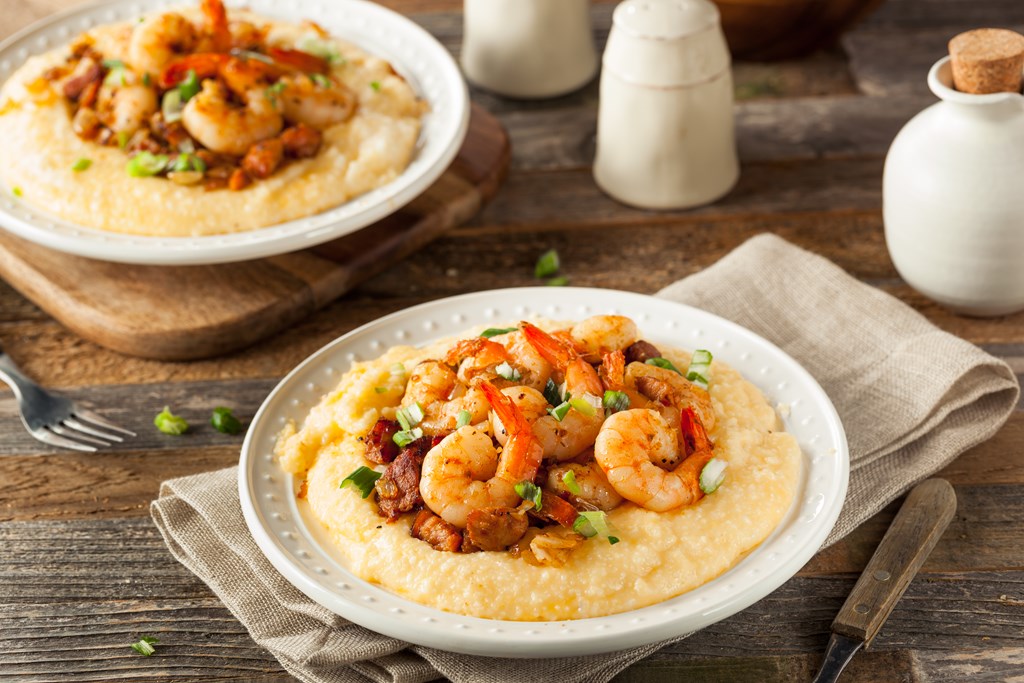Two bowls of shrimp and grits on a wooden table.