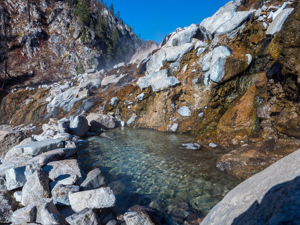 Hot Spring in Idaho with steam billowing during the morning on a clear day.