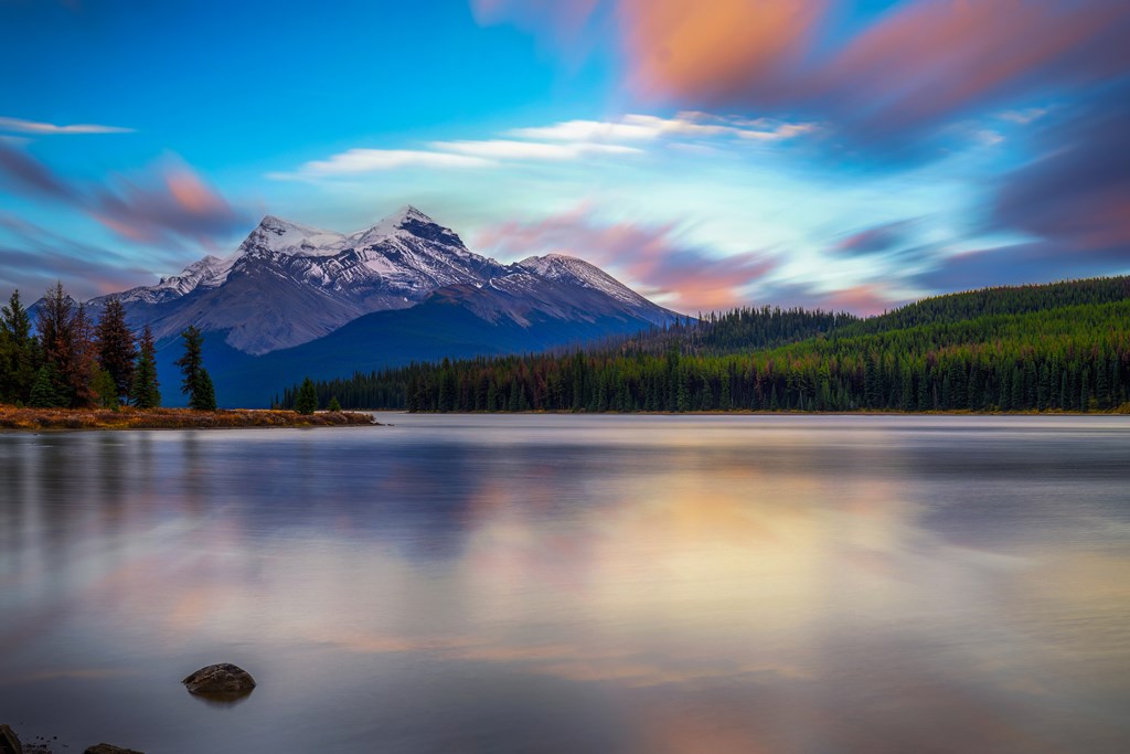 Sunset over Maligne Lake in Jasper National Park, Canada, with snow-covered peaks of canadian Rocky Mountains in the background. Long exposure.