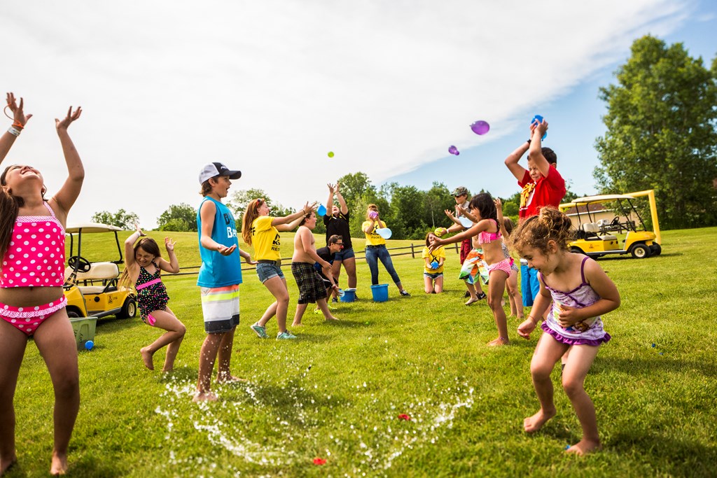 A group of kids throw water balloons during a planned activity at a KOA campground.