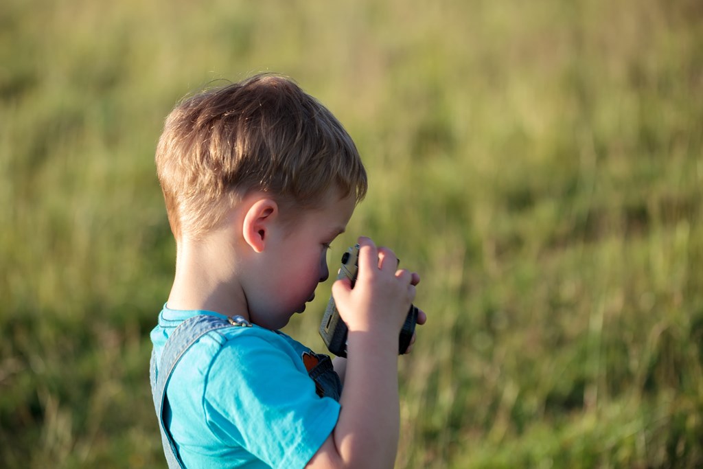Small boy with a camera in a field paints the scene for Missing, a kids spooky story