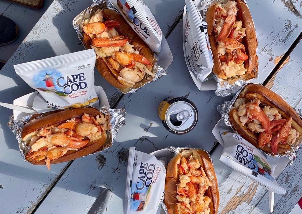 Top down view of five lobster rolls in paper serving boats.