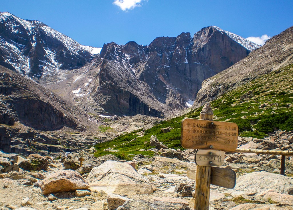 Longs Peak trail is rocky above the treeline. A signpost directs hikers.