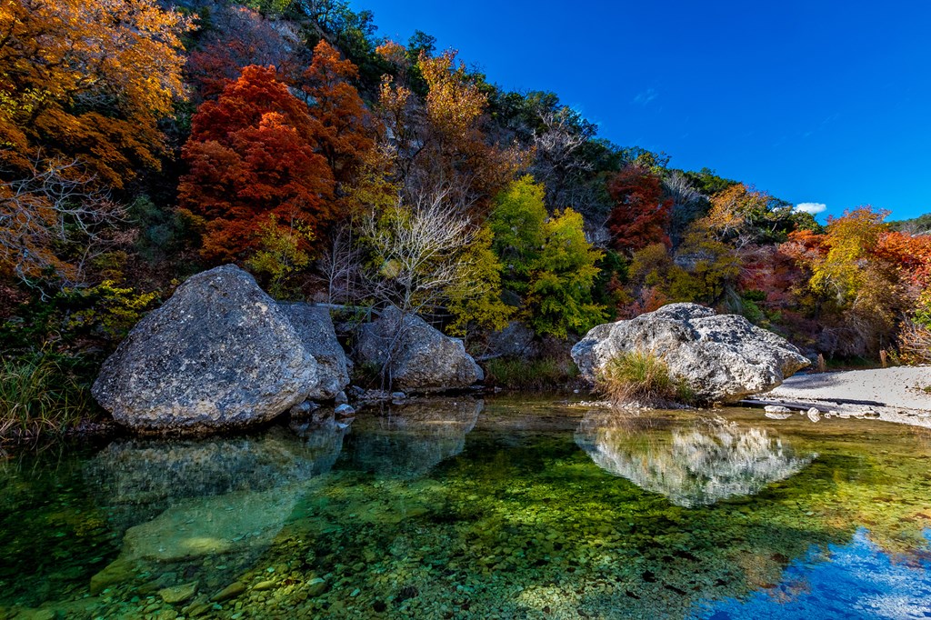 Beautiful Crystal Clear Pool with Several Large Boulders on Sabinal River with Amazing Very Bright Fall Foliage at Lost Maples State Park, Texas