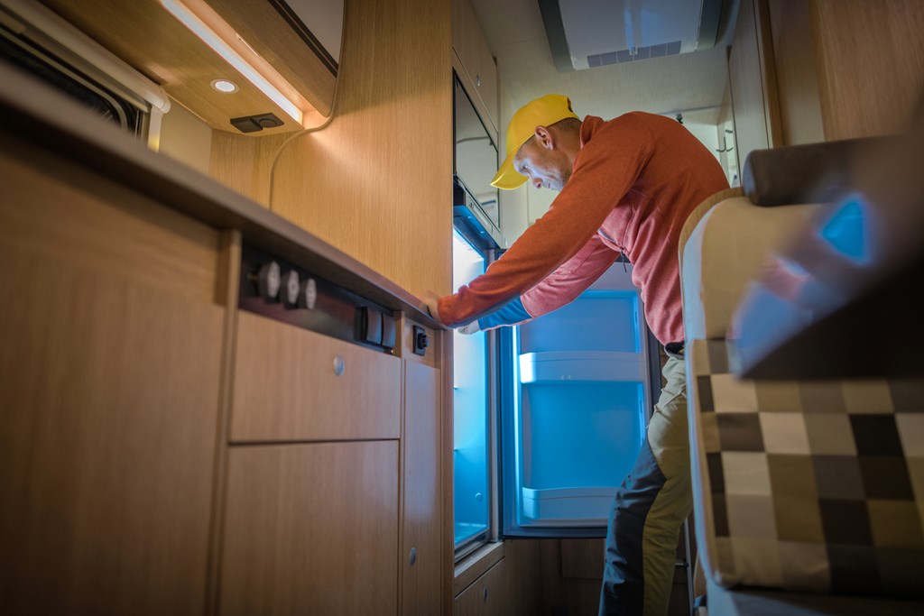 Man checking an RV refrigerator during dewinterization.