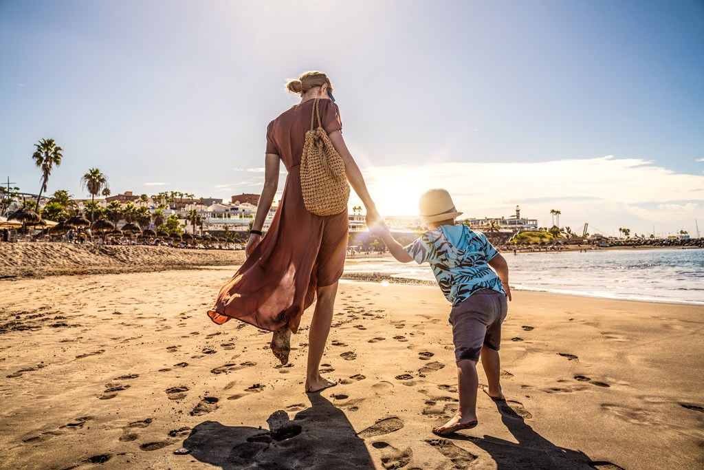 Mother and young son walking on a sunny beach.