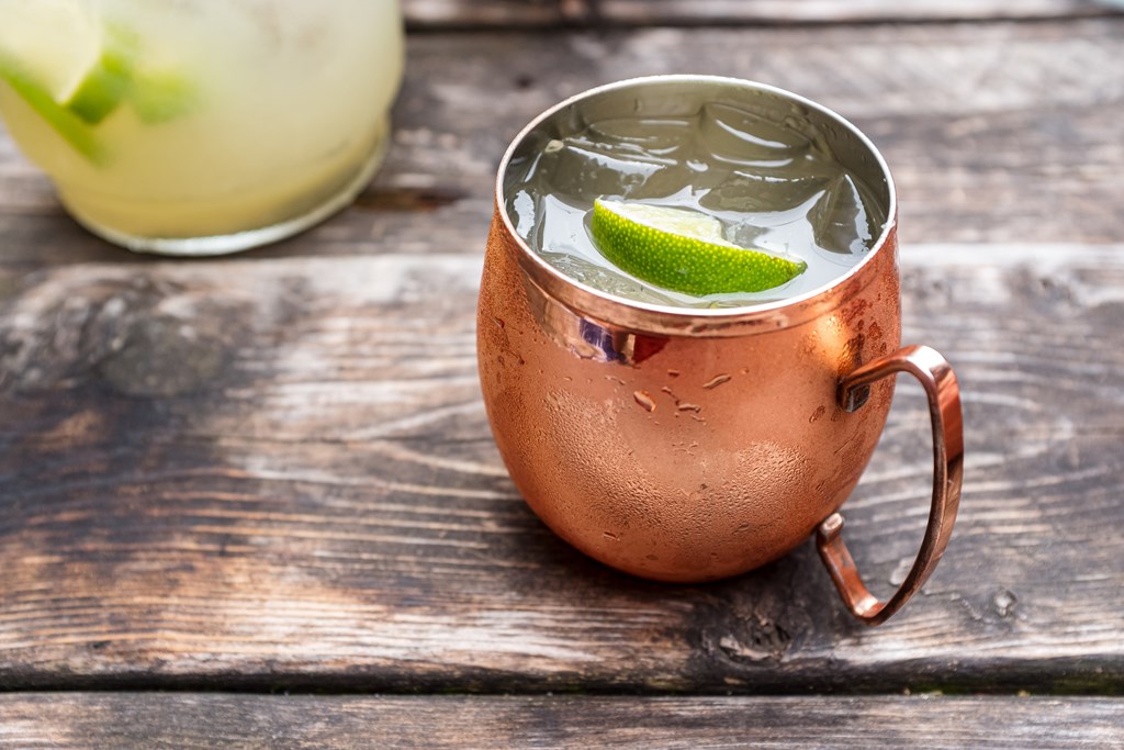 A Moscow Mule in a copper mug on an old wooden table.