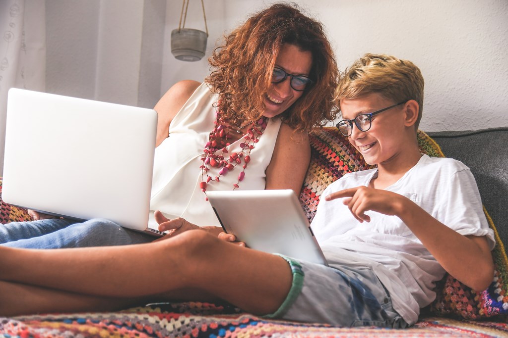 Mother and son planning a trip on their laptop and tablet.