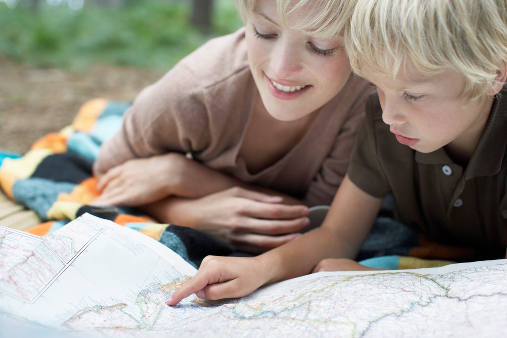 Closeup of a mother and sun looking at a map together outdoors.