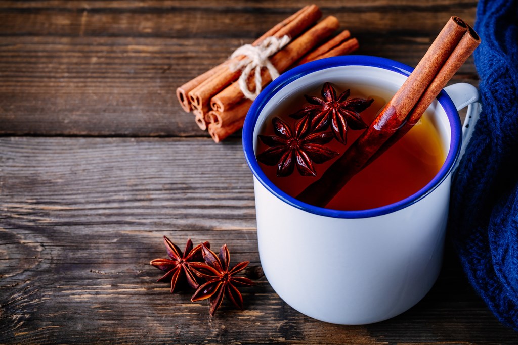Hot cider with spices cinnamon and anise in mug on dark wooden background