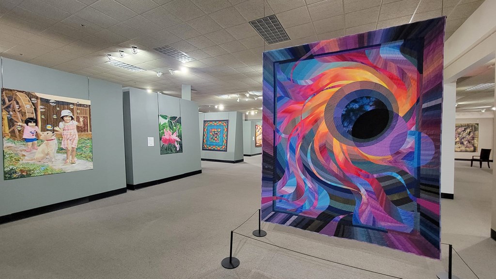 Quilts on display in a museum gallery.