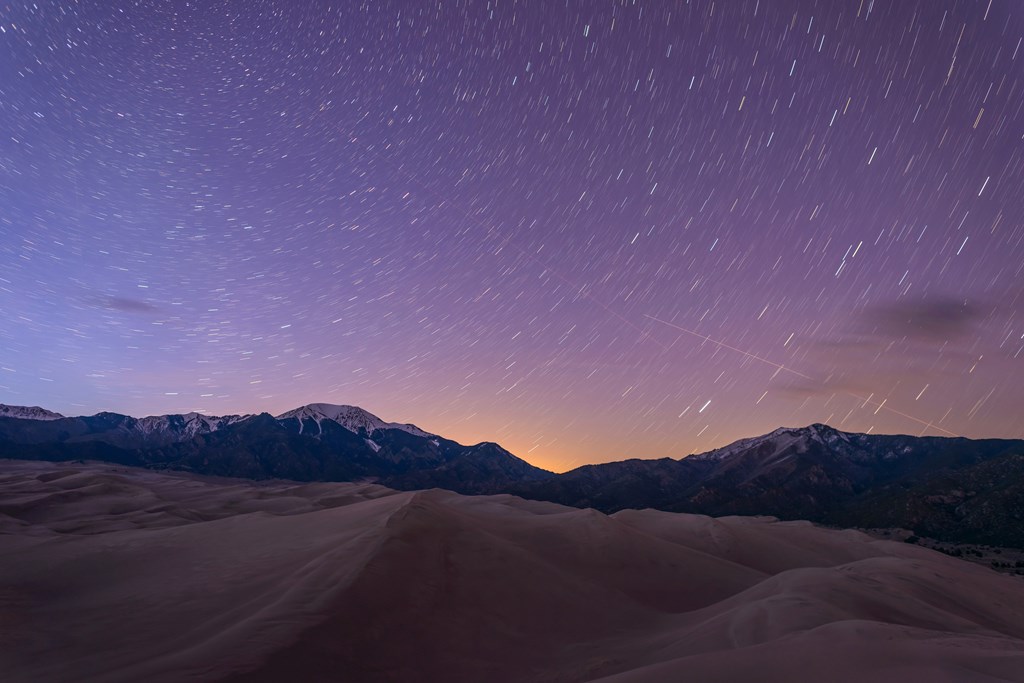 Timelapse photo of stars at dusk in Great Sand Dunes National Park.