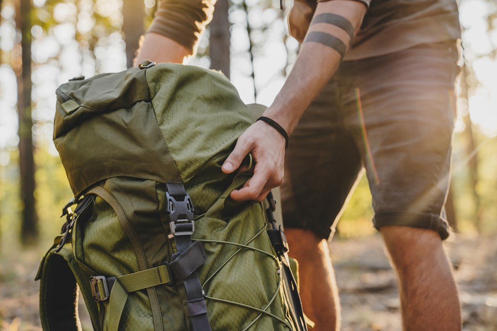 Close up of male hiker holding his camping backpack.