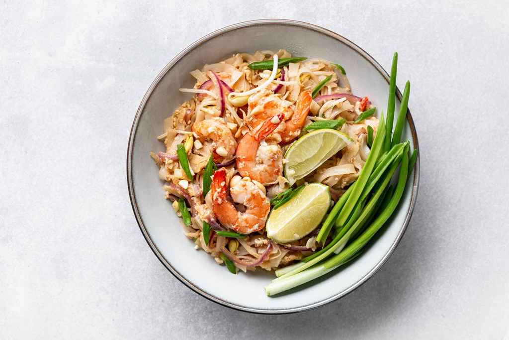 Pad Thai, Thai Fried Noodles with shrimp and vegetables on a light gray background, top view.