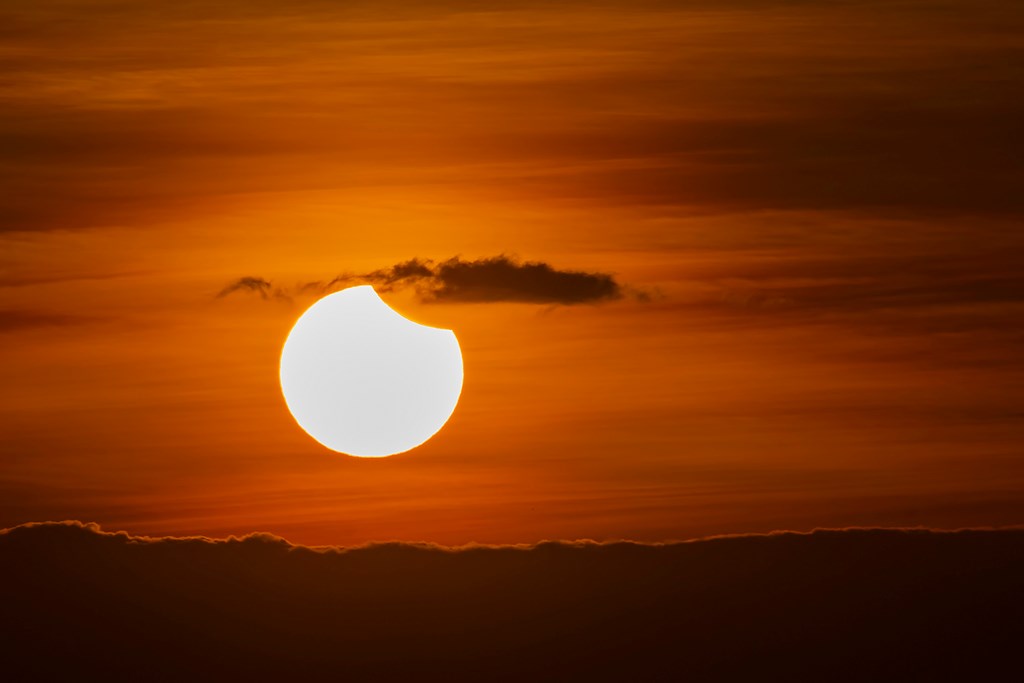 Beautiful moment of the sun eclipse during sunrise over the thick clouds.