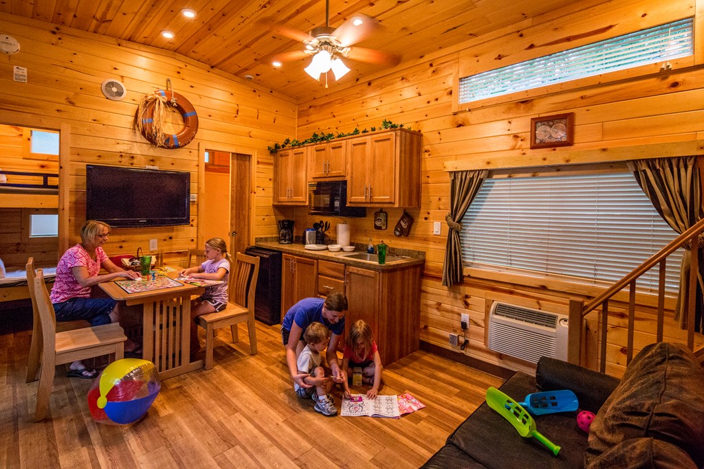 Kids play games on the floor of a KOA Deluxe Cabin while their mother looks on.